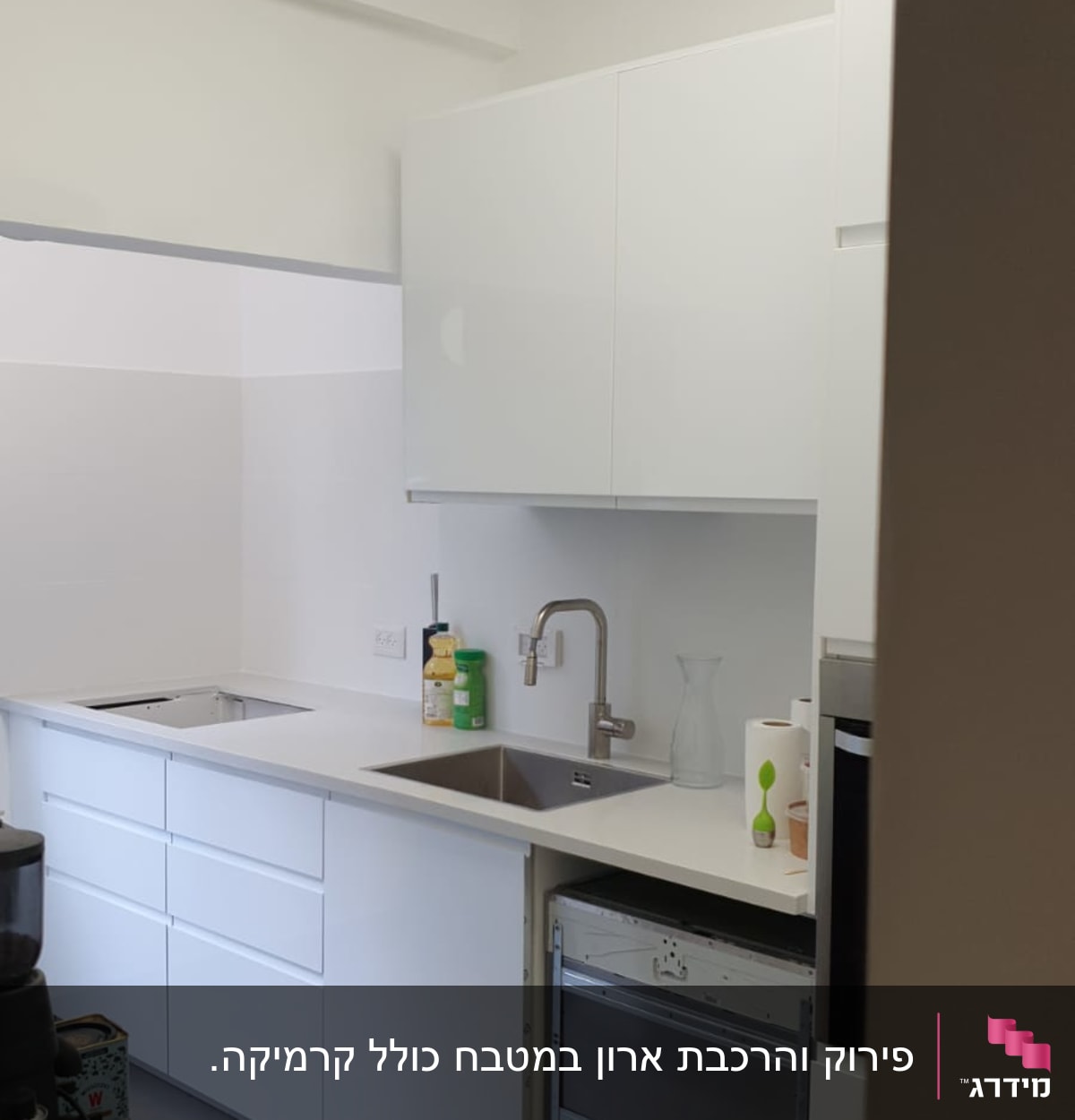 מטבח עם ארונות לבנים, כיור וברז מותקנים
